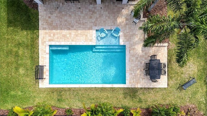 Aerial view of a backyard pool in Lake Nona, FL with a sunshelf and crystal-clear blue water