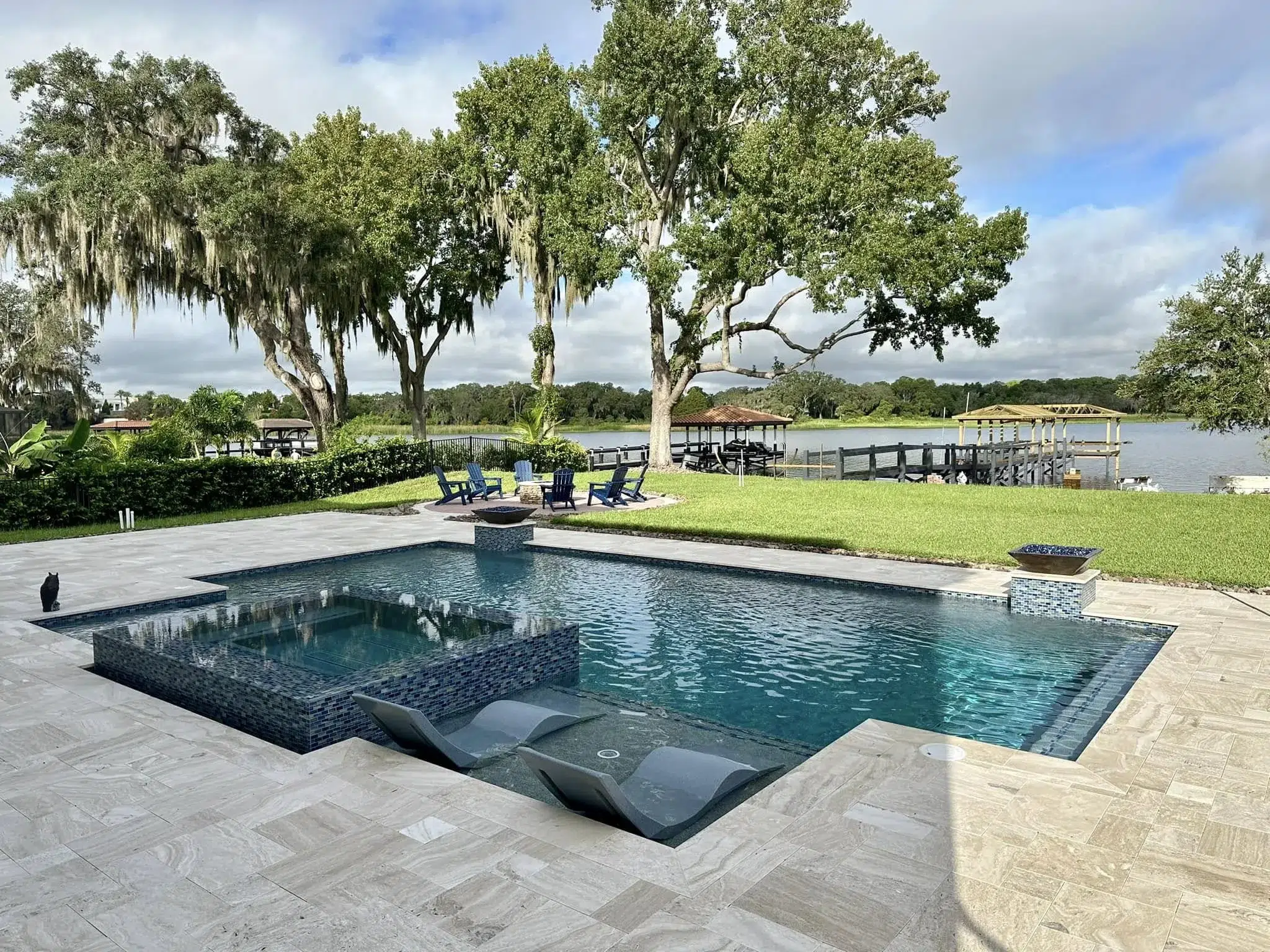 In-ground concrete pool in Orlando with raised spa, tanning ledge, and stone decking beside a lakefront backyard