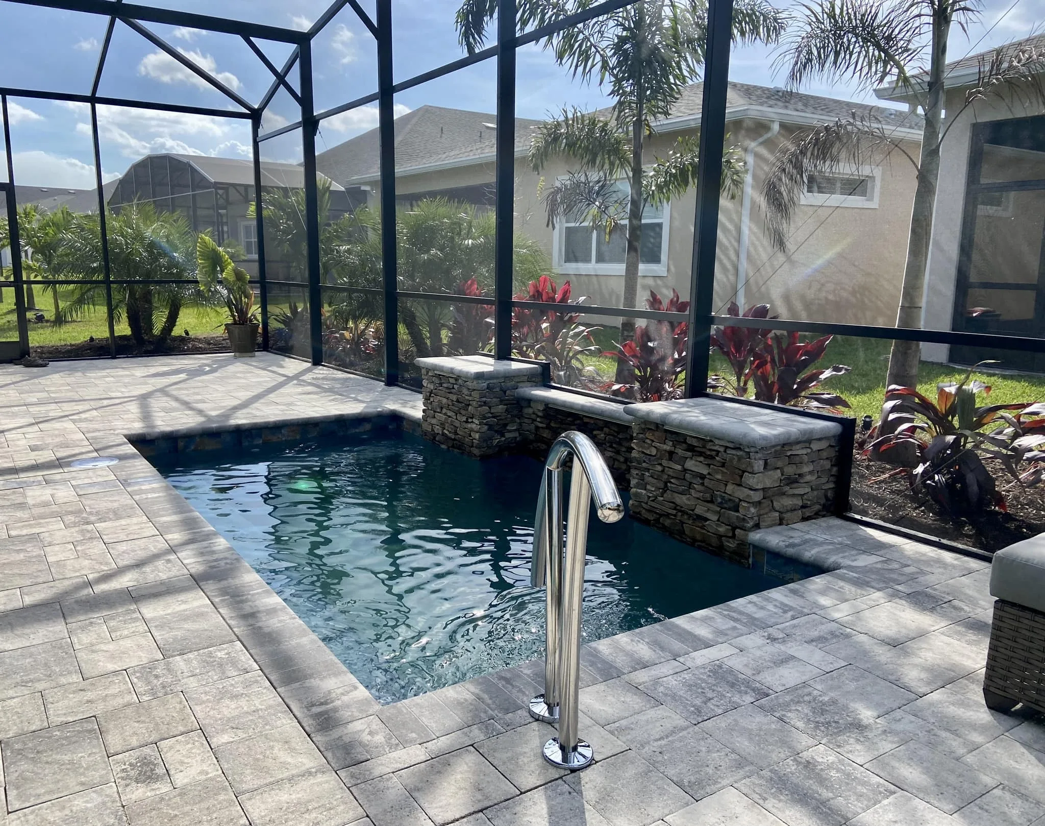 Custom concrete plunge pool with paver decking and screened enclosure designed to fit a small Orlando backyard.