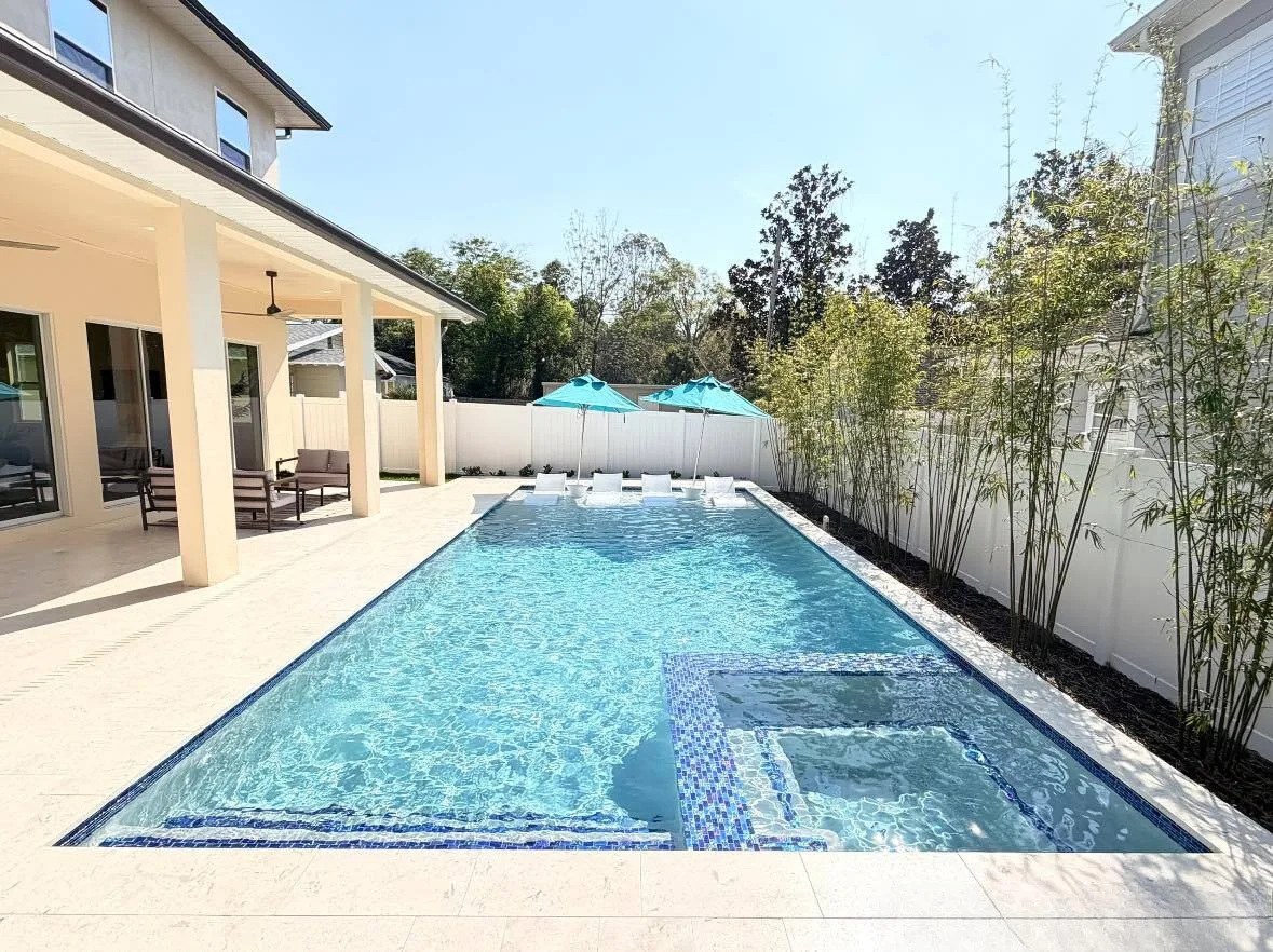 Modern custom pool in Orlando backyard with tanning ledge, spa section, and patio—example of design features that impact overall pool budget and construction costs.