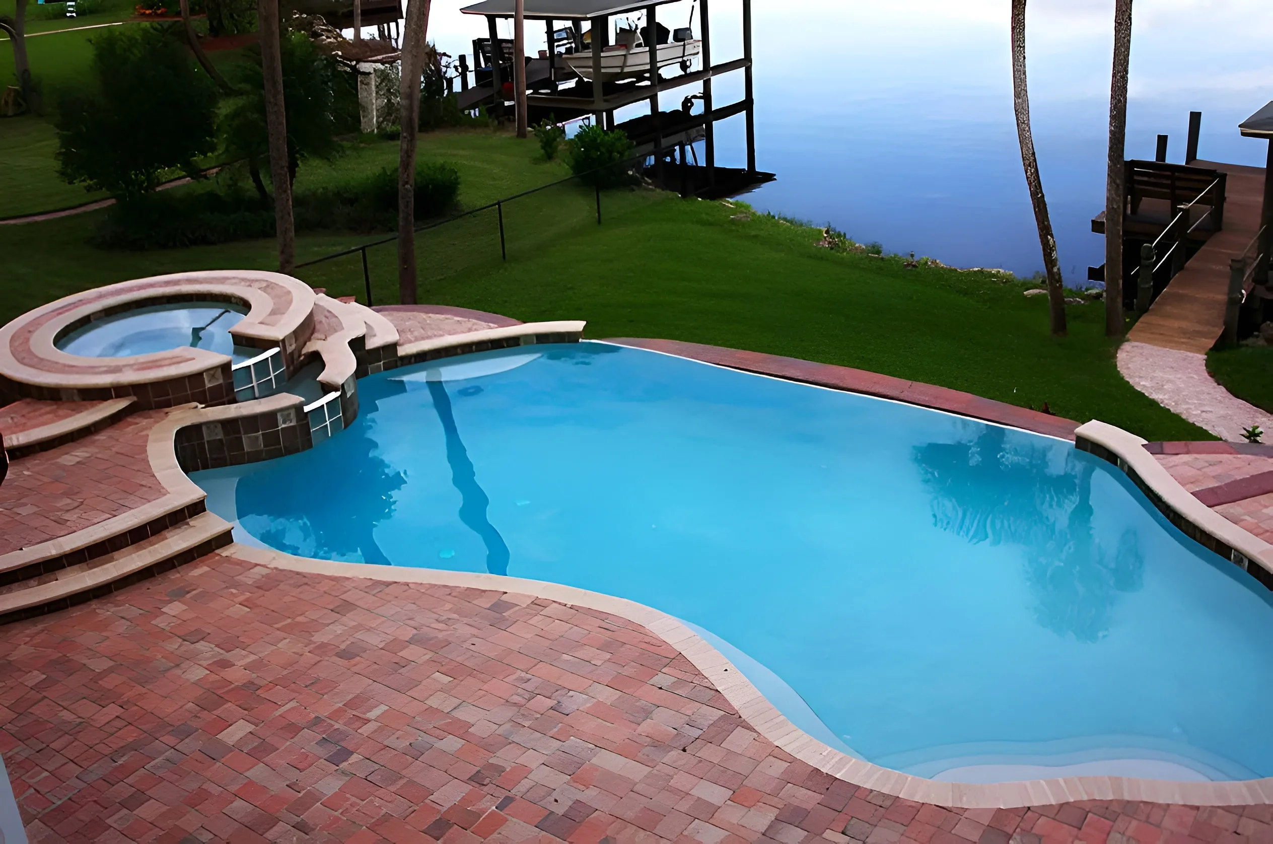 Residential swimming pool with spa and paver deck in a coastal waterfront setting, illustrating how ocean air and coastal weather influence pool planning and design in Daytona Beach