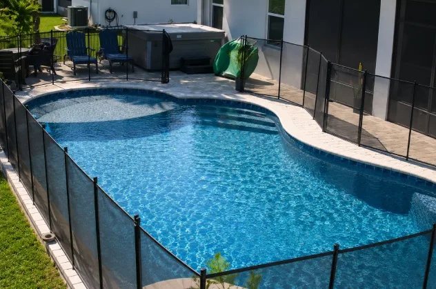 Freeform backyard pool with a shallow sun shelf, entry steps, paver deck, and removable safety fence in Daytona Beach