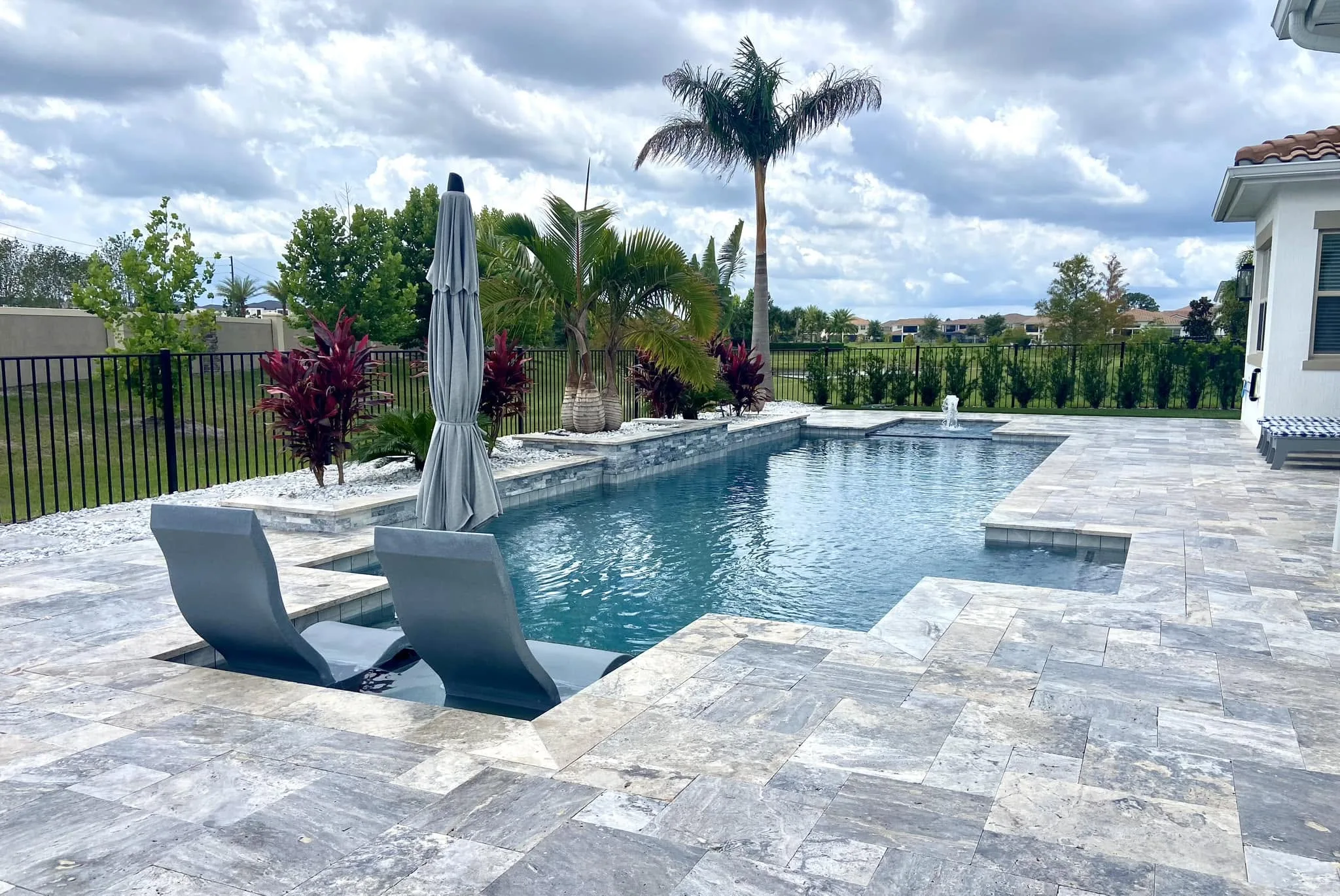 Geometric backyard pool with straight edges, tanning ledge, and integrated water feature